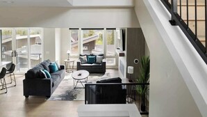 Un vaste espace de vie comprenant un canapé moderne, une table basse et un escalier menant à un niveau supérieur.