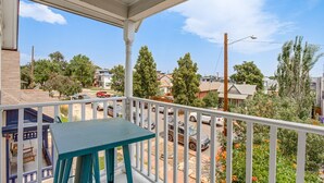 Ein Balkon mit Blick auf eine Wohnstraße, ein parkendes Auto und einen klaren Himmel.