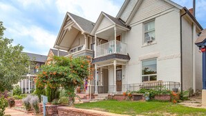 Ein zweistöckiges Haus mit Balkon, Veranda und einem gepflegten Garten.