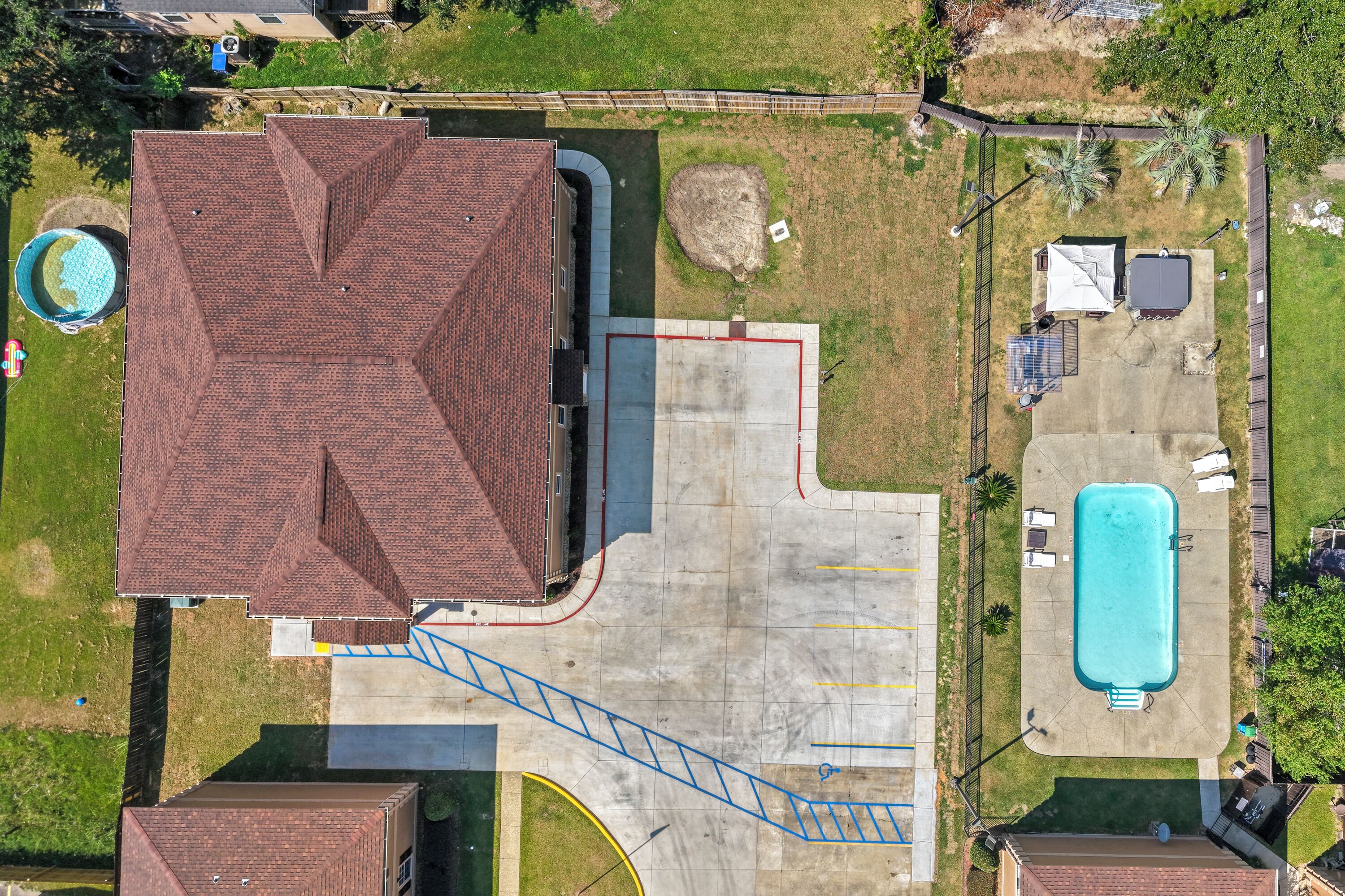 Oversigtsbillede af en boligejendom med et stort murstenshus, swimmingpool og en indhegnet have.
