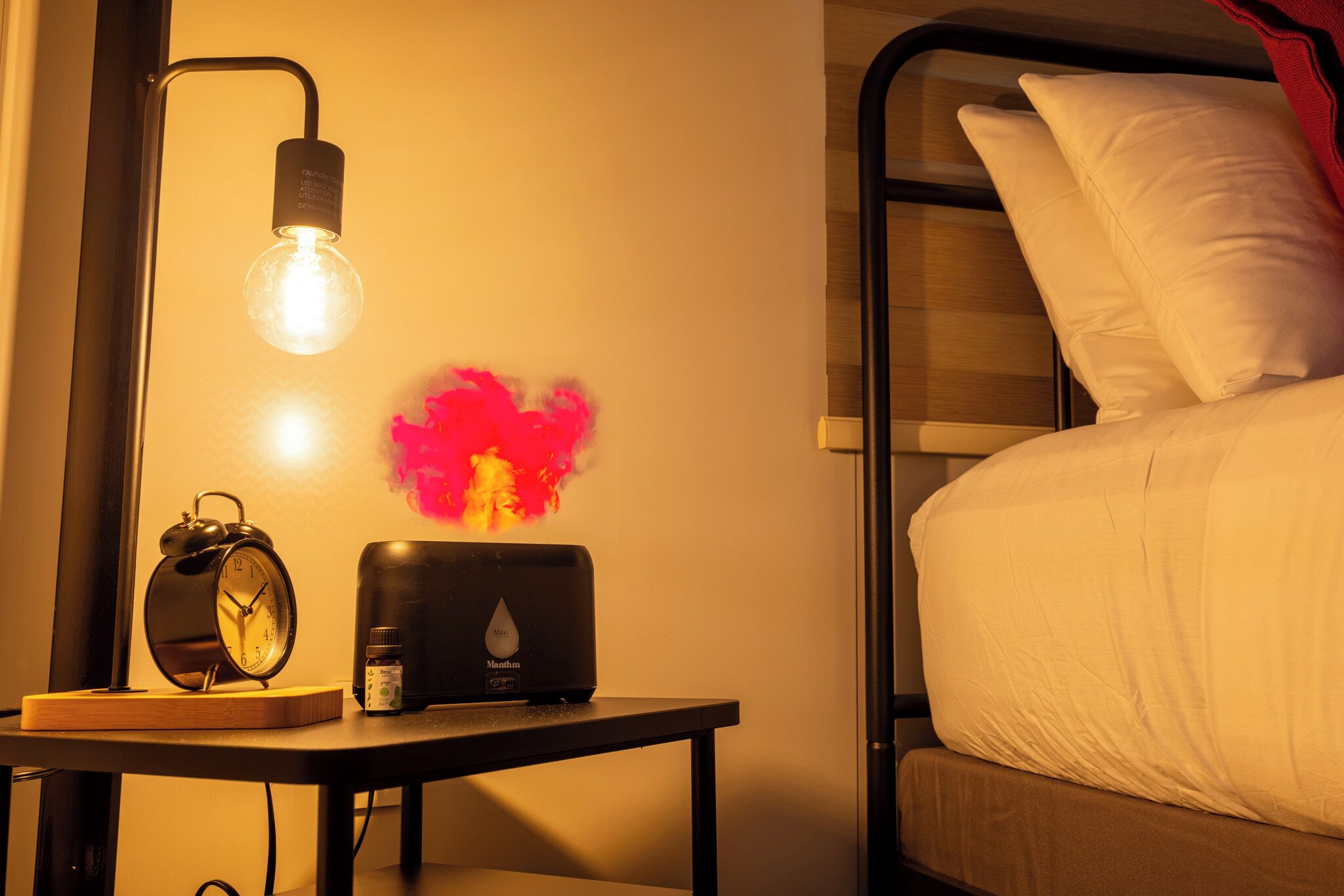 A bed with white bedding, a nightstand with a clock, a lamp, and a decorative item.