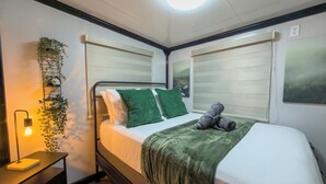 Ein ordentlich eingerichtetes Schlafzimmer mit Bett, Nachttisch und einer hängenden Pflanze.