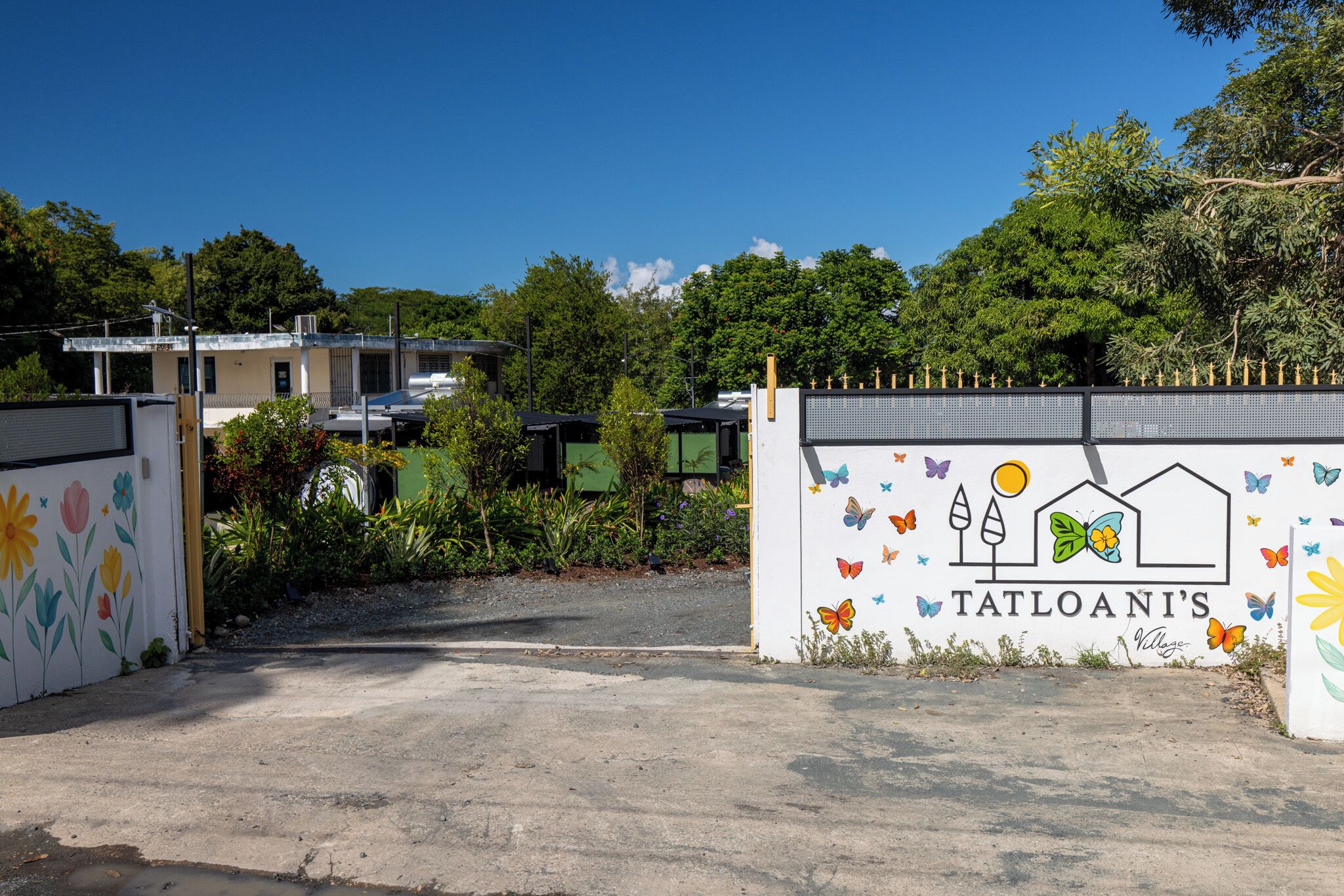 A gated entrance with a colorful mural and the name "Tatloani's" on the gate.
