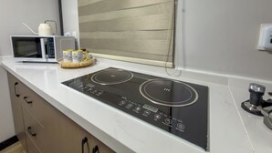Eine Küchenzeile mit Mikrowelle, Kaffeemaschine und integriertem Induktionskochfeld.