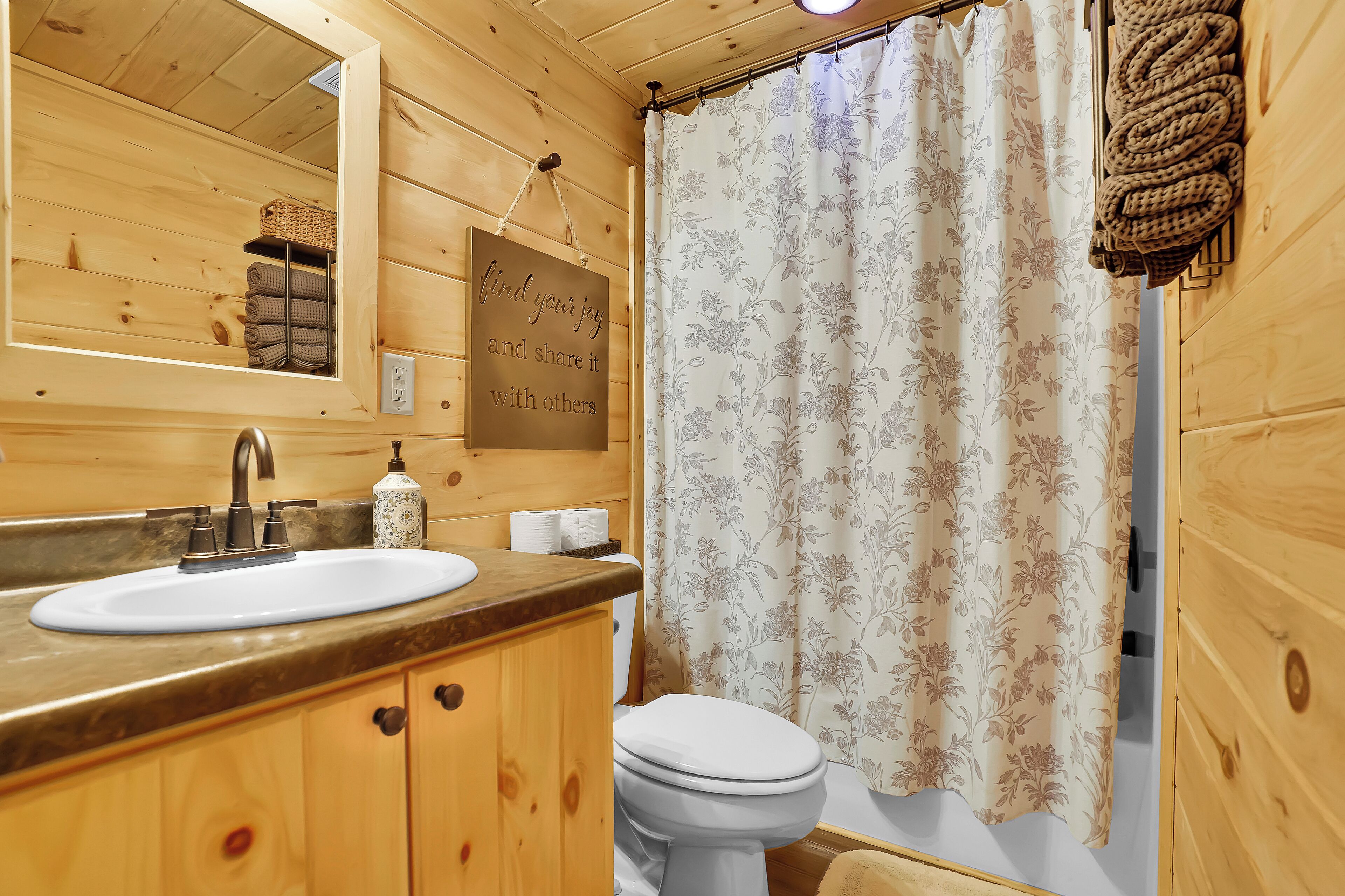 Een houten badkamer met een wastafel, spiegel en toilet.