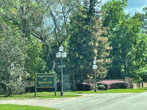 A street sign for Aspenwood at Grendale, a private community, with a street lamp and lush greenery in the background.
