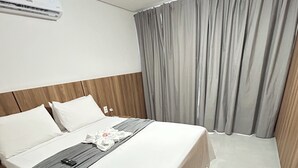 A neatly made bed with a grey blanket and a remote control on it.