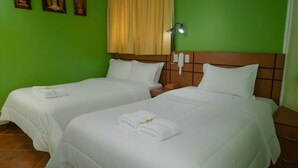 A hotel room with two beds, each with white linens and towels, a wooden headboard, a bedside lamp, and a telephone. - Rey Palace (Cajamarca)