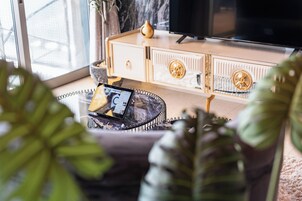 Una sala de estar moderna con un sofá, una mesa de centro con una tablet, un televisor y elementos decorativos.