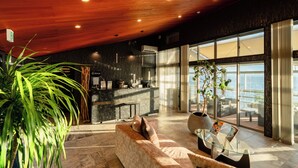 A modern interior with a wooden ceiling, a sofa, a coffee table, and a view of the sea through large windows. - Glamping  Resort WOOD DESIGN PARK NOMA (Mihama)