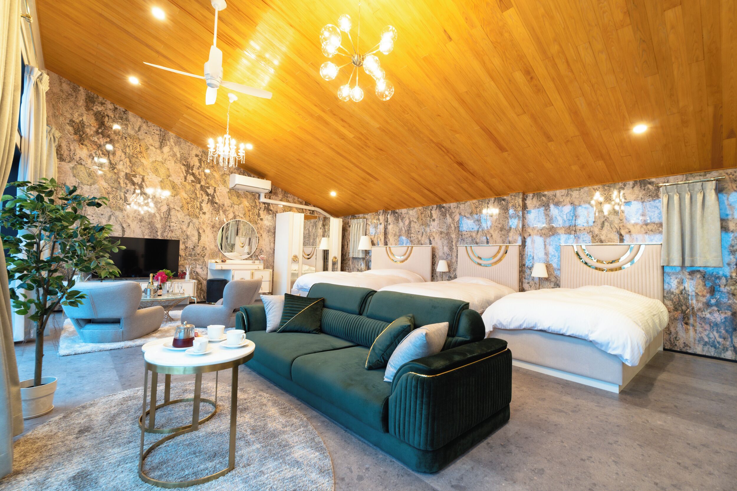 A modern hotel room with a wooden ceiling, a green sofa, a bed, and a television.