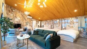 A modern hotel room with a wooden ceiling, a green sofa, a bed, and a television.
