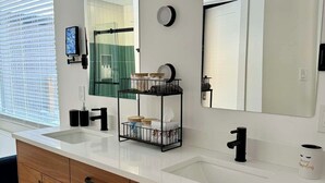 Une salle de bain moderne avec deux vasques, des meubles en bois et un grand miroir.
