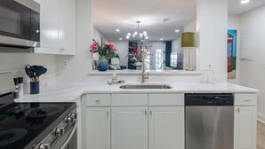 A modern kitchen with white cabinetry, a stainless steel dishwasher, and a black stove. - Modern Upgrades & Comfort (Oxford)