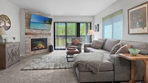 Ein Wohnzimmer mit Kamin, einer Couch, einem Couchtisch und Blick durch eine Glastür.
