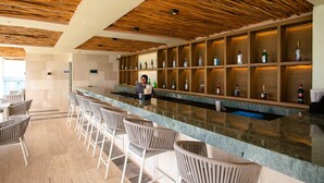 Eine Bar mit Holzbalkendecke, Barhocker und Regalen voller Spirituosenflaschen.