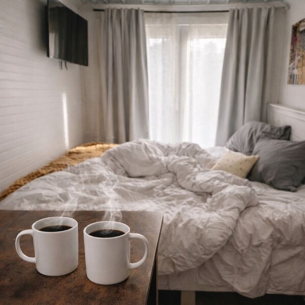 A bedroom with a bed, two white mugs on a table, and a window with curtains. - A Sweet Spot• Hot Tub 13 min to Franklinton and 19 min the State Park (Mount Hermon)
