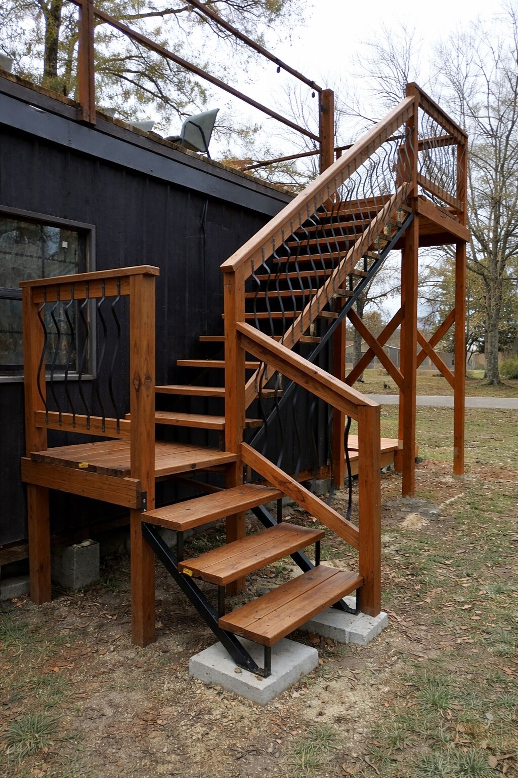 Una escalera exterior de madera con barandales metálicos, que conduce a un edificio de aspecto oscuro.