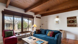 Una sala de estar acogedora con un sillón rojo, un sofá azul y una mesa de centro de madera.