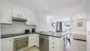 A modern kitchen with white cabinets, a built-in oven, a dishwasher, and a black countertop. - Shoreline Apartments - Unit 4a (Bargara)