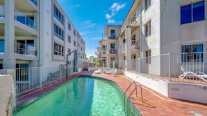 A residential building with a swimming pool, balconies, and a clear blue sky. - Shoreline Apartments - Unit 4a (Bargara)
