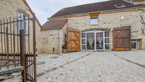 A stone building with a gravel driveway, wooden shutters, and a metal gate. - Le Gite du Relais - PARGUES (PARGUES)