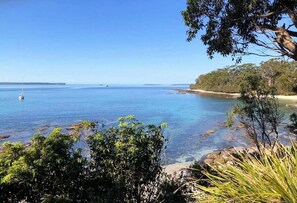 A coastal landscape with clear blue waters, a sandy beach, and dense greenery. - Salt & Kin Huskisson (Huskisson)