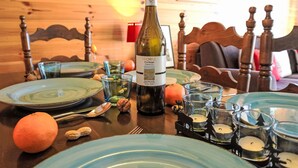Una taula de dinar de fusta amb ampolla de vi, plats, gots i espelmes.