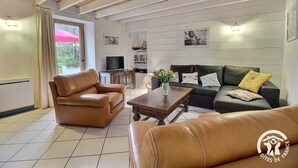 Una sala de estar amoblada con un sofá, dos sillones, una mesa de centro y un televisor.