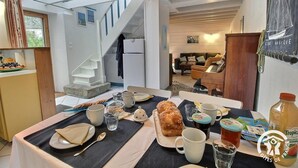 Un comedor con una mesa dispuesta para el desayuno, incluyendo pan, bollería y una botella de zumo de naranja.