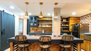 Una cuina moderna amb una illa central, tamboretes de bar, il·luminació penjant i detalls de fusta.
