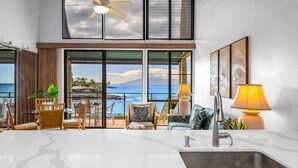 Cocina moderna con una isla grande, comedor con sillas y vista al océano.