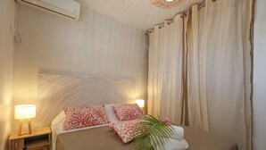 Un letto rifatto con cura, una testiera decorata, una lampada da comodino e un asciugamano con una foglia di palma.