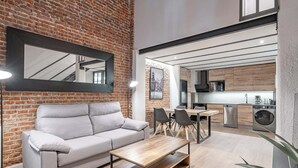 A modern living room with a grey sofa, wooden coffee table, and a brick wall. - Deluxe Prosperidad Apartment (Madrid)