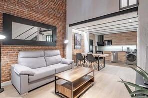 A modern living room with a grey sofa, wooden coffee table, and a brick wall. - Deluxe Prosperidad Apartment (Madrid)