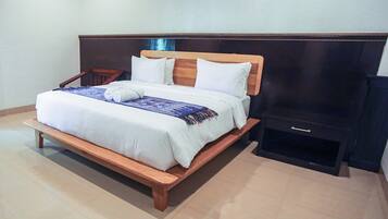 A neatly made bed with a wooden headboard, a bedside table, and a dark nightstand.