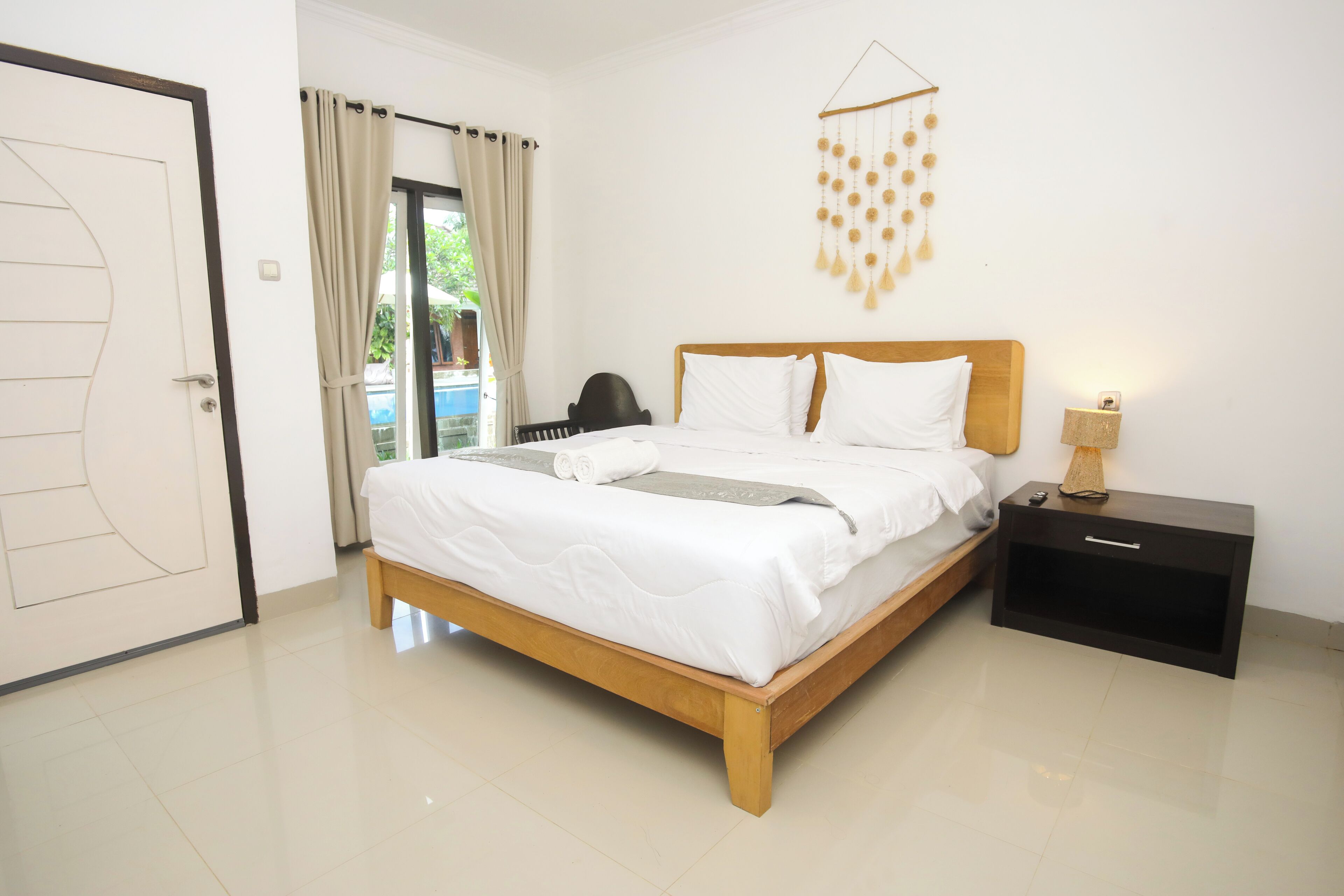 A neatly made bed with white linens, a wooden headboard, and a bedside table with a lamp.