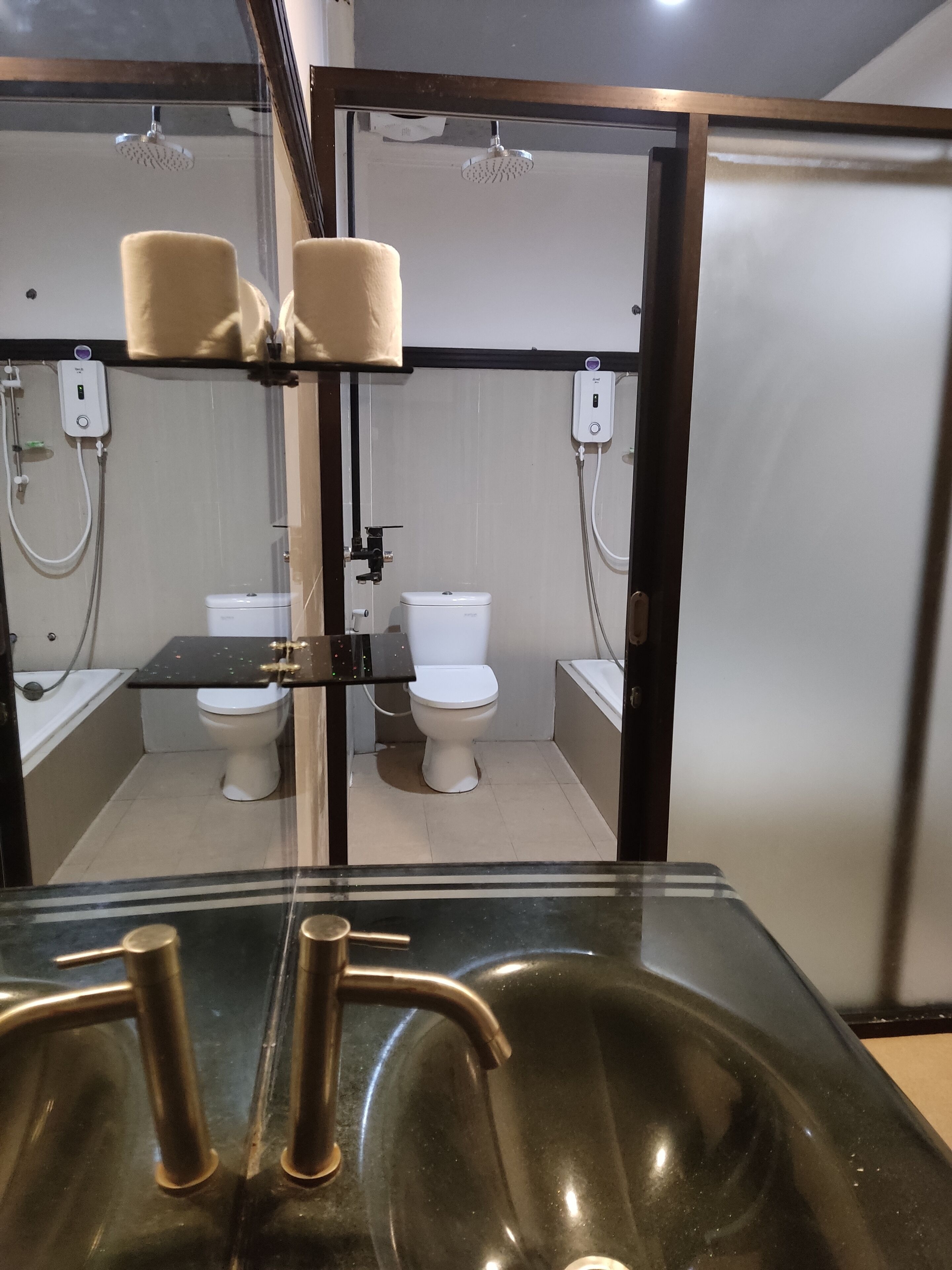 Un baño con dos inodoros, una ducha y un lavamanos.