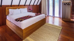 Un dormitorio con cama de madera, un ventanal con cortinas y un armario de madera con una percha.