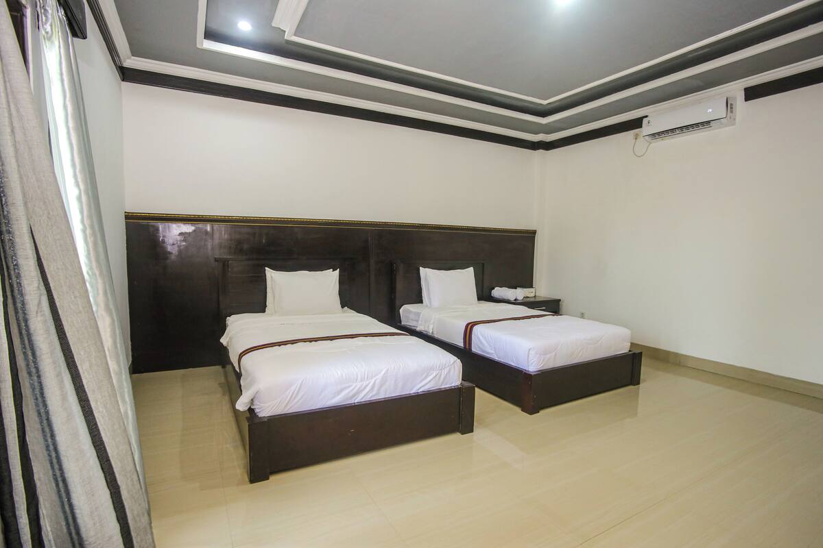 Una habitación de hotel con dos camas, una mesita de noche y un equipo de aire acondicionado.