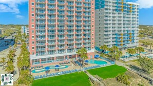 Un hotel de varios pisos con balcones, piscina y jardines.