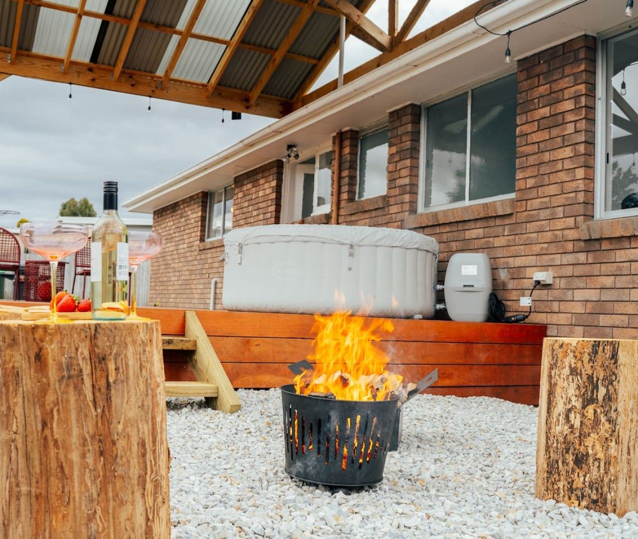 Un espace barbecue extérieur avec un foyer, un gril et un banc pour s’asseoir.