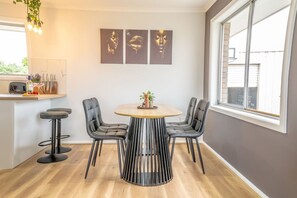Uma sala de jantar com uma mesa redonda, quatro cadeiras e uma janela.