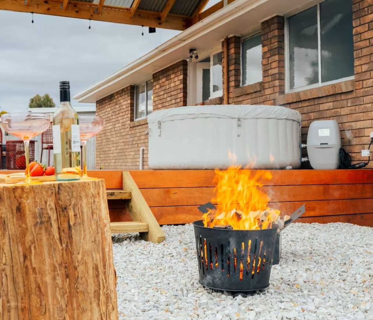 A backyard with a fire pit, a wooden bench, and a barbecue grill.