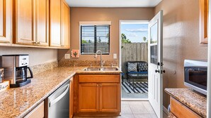 A compact kitchen with wooden cabinets, a built-in microwave, and a coffee maker. - Point Loma Hideaway · Relaxing Hot Tub + AC (San Diego)