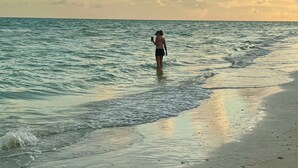 En person står på en strand med hav og en overskyet himmel i baggrunden.