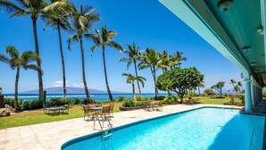 Una piscina con acqua cristallina, circondata da palme e vista sull'oceano.