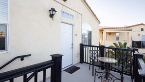 Ein Balkon mit einer weißen Tür, einem kleinen Tisch und Stühlen.