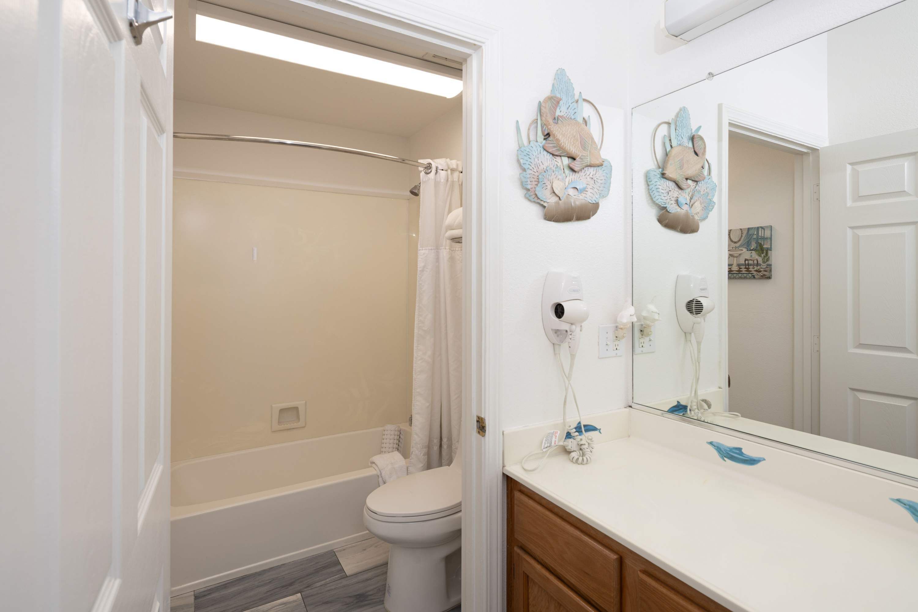 A bathroom with a shower, toilet, and vanity with a mirror.