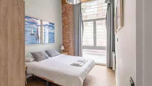 Ein modernes Schlafzimmer mit einem großen Bett, einer Ziegelwand und einem Fenster mit Vorhängen.